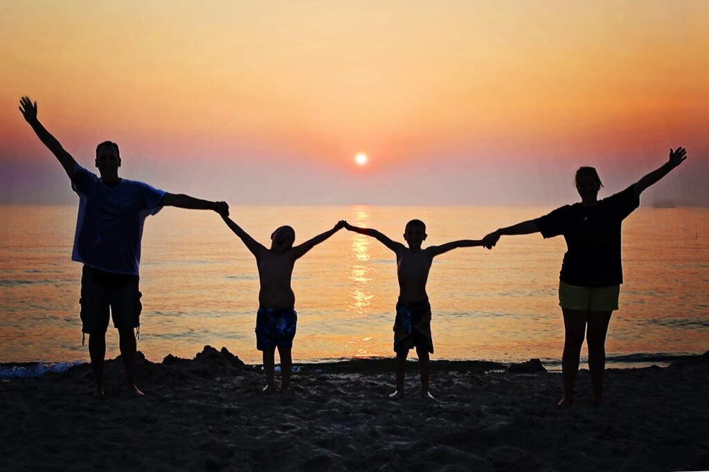 Family holding hands together on beach happy and smiling sunset after eating a meal and seeing dietitian via telehealth online.jpg
